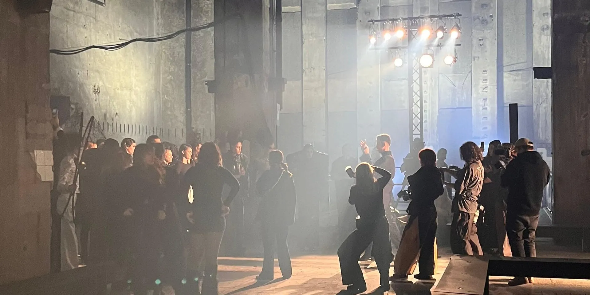 Gäste in einer Industriehalle vor illuminierter Bühne